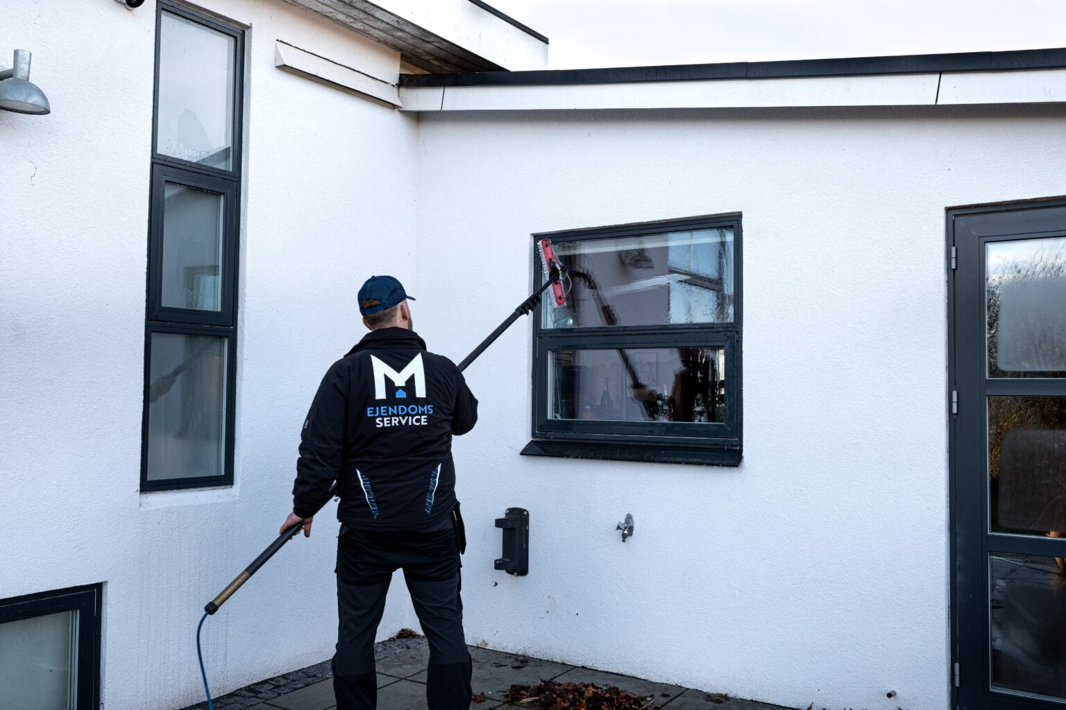 Professionel vinduespudser rengør vindue på hus