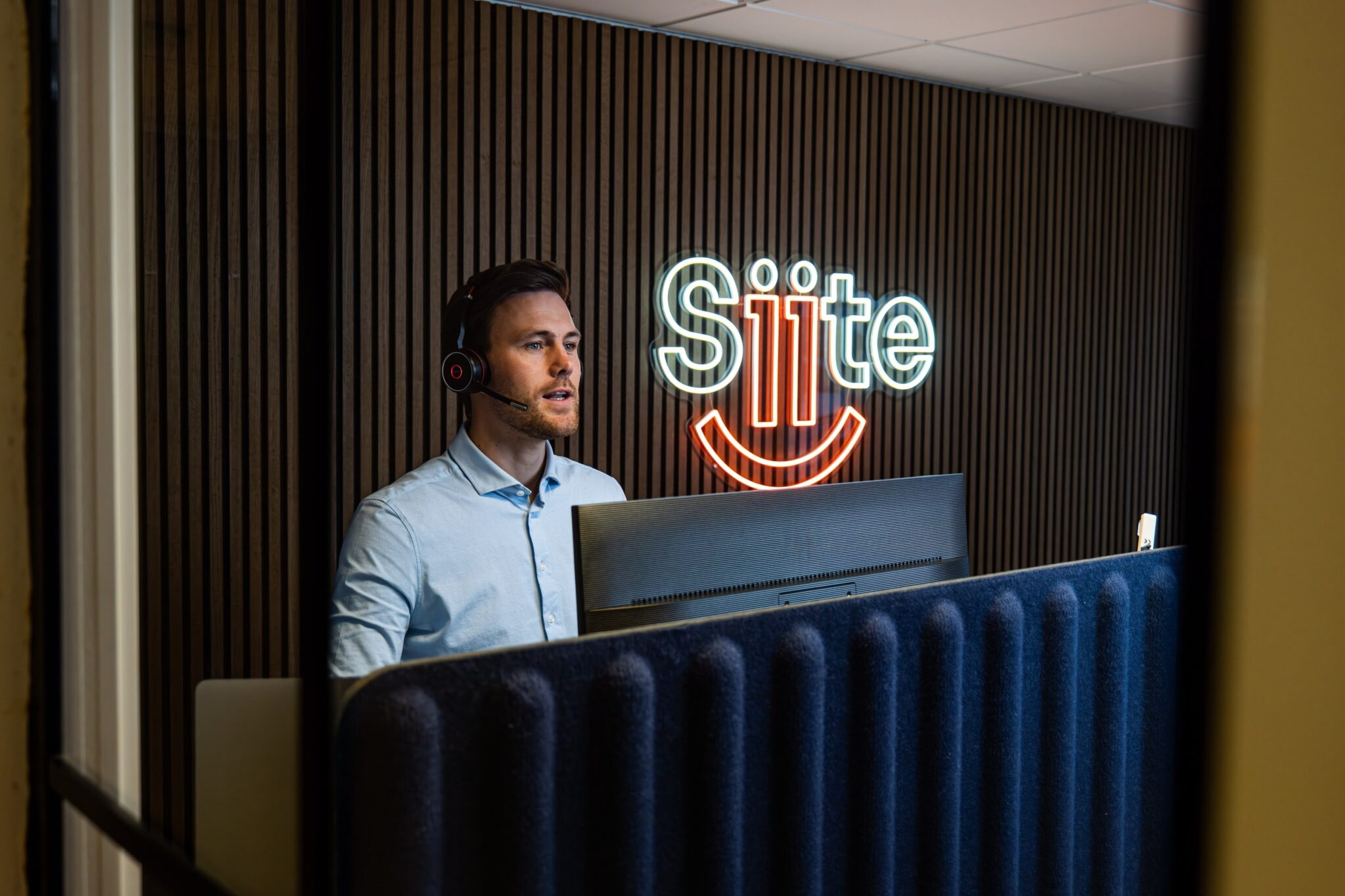 Mand foran computer med headset i kontor